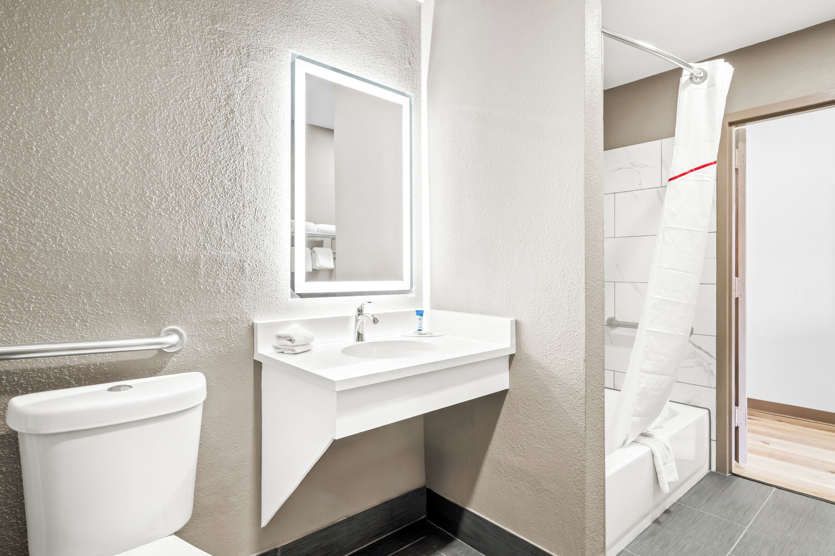 Une salle de bain moderne avec un lavabo blanc, un miroir et des toilettes.