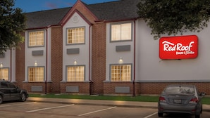 A Red Roof Inn & Suites building with a brick facade, multiple windows, and a parking lot. - Red Roof Inn & Suites Euless - DFW Airport Southwest (Euless)