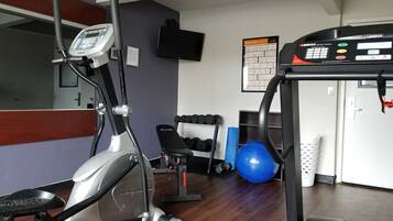 A gym with cardio equipment, dumbbells, and exercise balls.