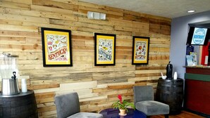 A reception area with a wooden wall, framed posters, a coffee machine, chairs, and a small table with a plant. - Microtel Inn & Suites by Wyndham London (London)