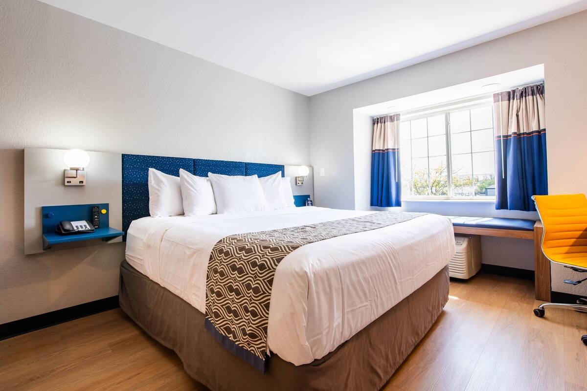 A hotel room with a large bed, bedside tables, a desk, and a chair.