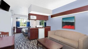 A compact room with a kitchenette, a sofa, a dining table, and a TV mounted on the wall. - Microtel Inn & Suites by Wyndham London (London)