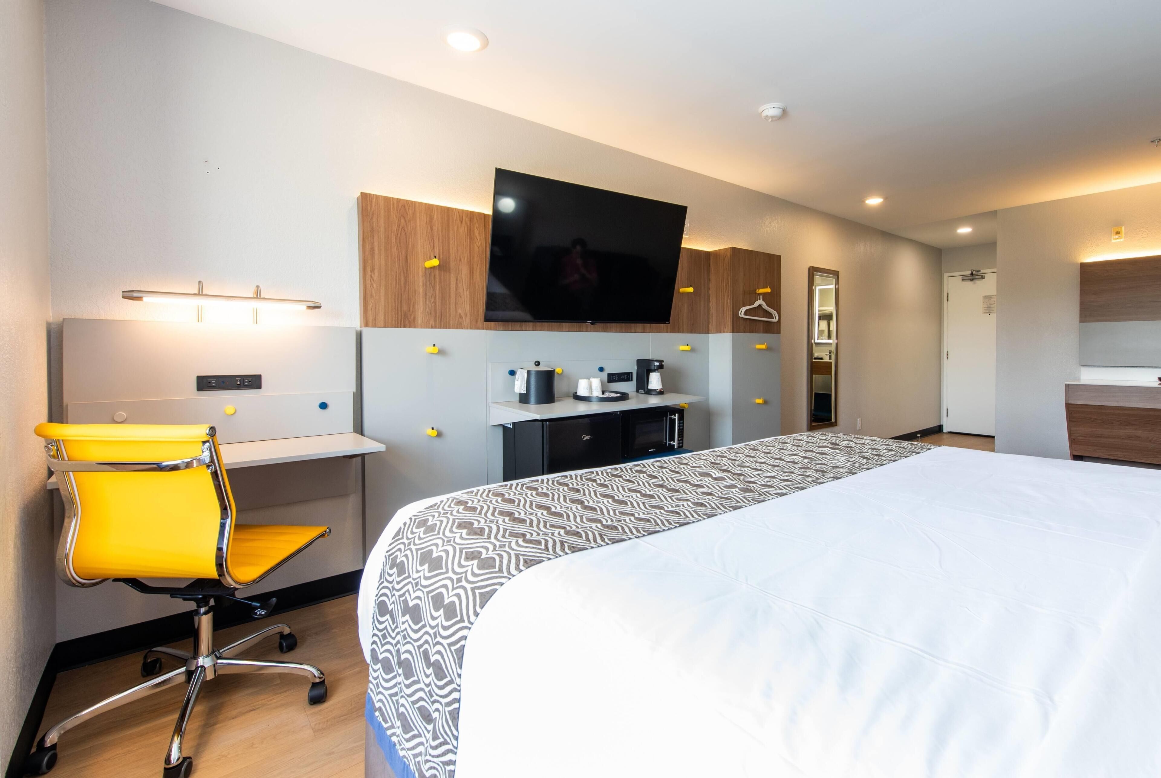 Ein Hotelzimmer mit Bett, Schreibtisch mit Stuhl, Fernseher und Kleiderschrank.