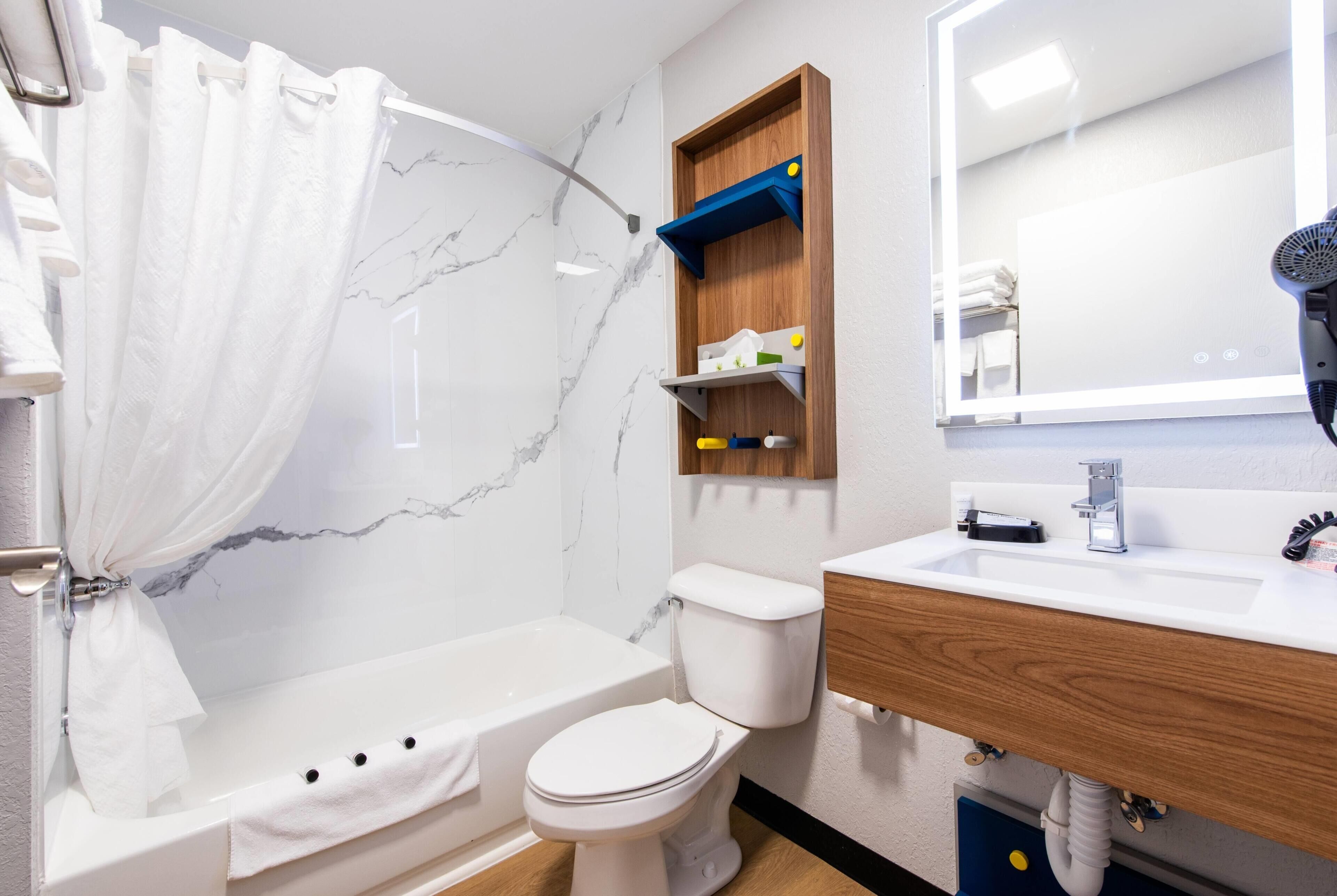 A bathroom with a bathtub, toilet, vanity, and a mirror.