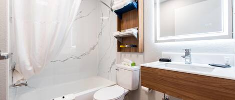 A modern bathroom with a bathtub, toilet, and vanity.