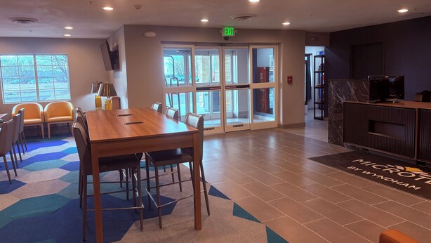 A conference room with a large table and chairs, a reception desk, and a view through glass doors.