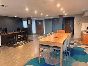 A hotel reception area with a reception desk, a conference table, and a kitchenette.