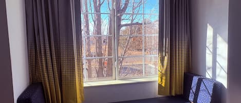 Um quarto com uma janela grande, um banco e cortinas.