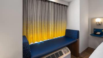 Een kamer met een bankje, een wandradiator en een nachtkastje met een lamp.