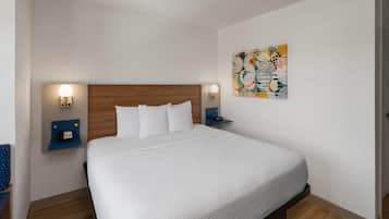 Une chambre d’hôtel avec un grand lit, deux tables de chevet, une œuvre d’art accrochée au mur et un plancher en bois.