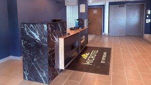 A reception area with a marble counter, a digital screen, and a sign indicating a check-in time of 10:00 AM.