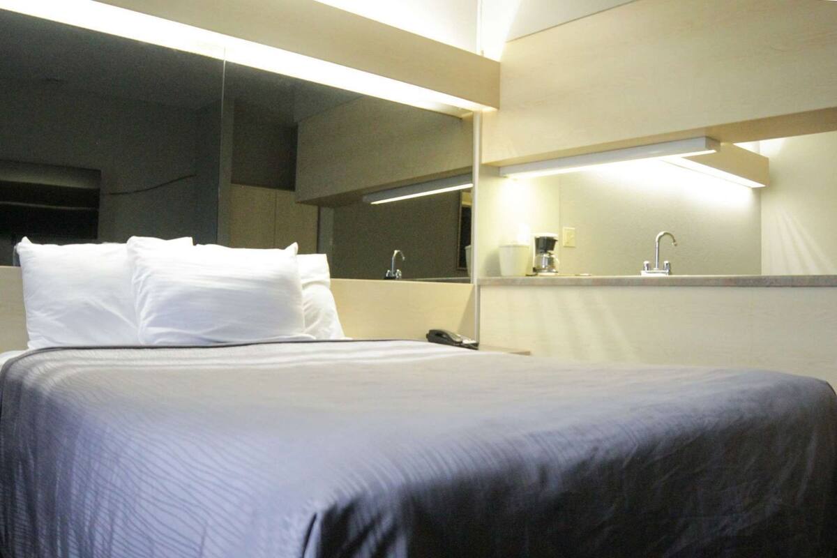 Ein Hotelzimmer mit Bett, Nachttisch, Spiegel und Beistelltisch.