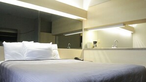 A hotel room with a large bed, a bedside table, a mirror, and a sink. - Americas Best Value Inn & Suites Jackson, TN (Jackson)