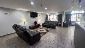 A living room with two leather sofas, a small table with a lamp, and a TV mounted on the wall. - Americas Best Value Inn & Suites Jackson, TN (Jackson)