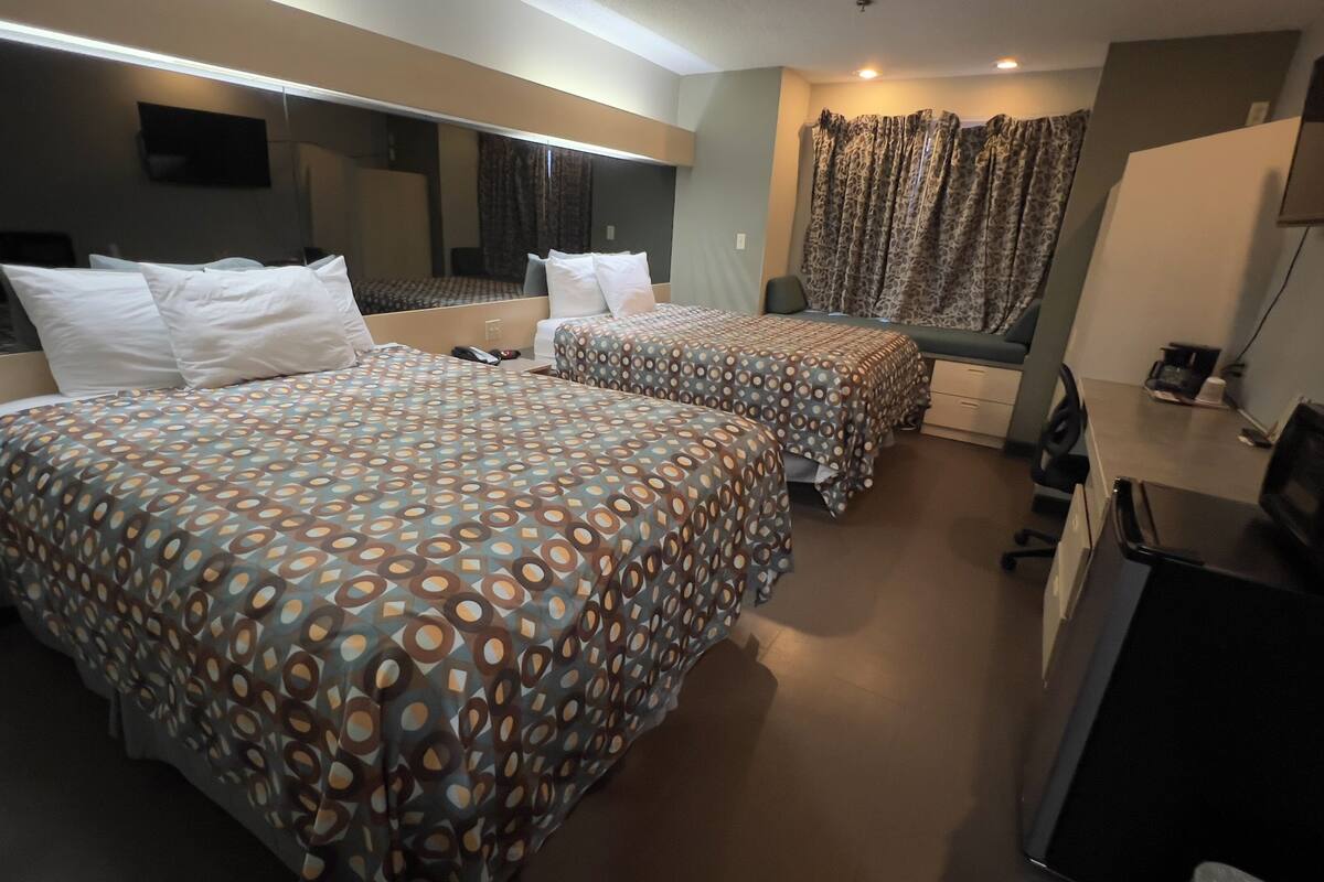 Ein Hotelzimmer mit zwei Betten, einem Schreibtisch, einem Fernseher und einer Mikrowelle.