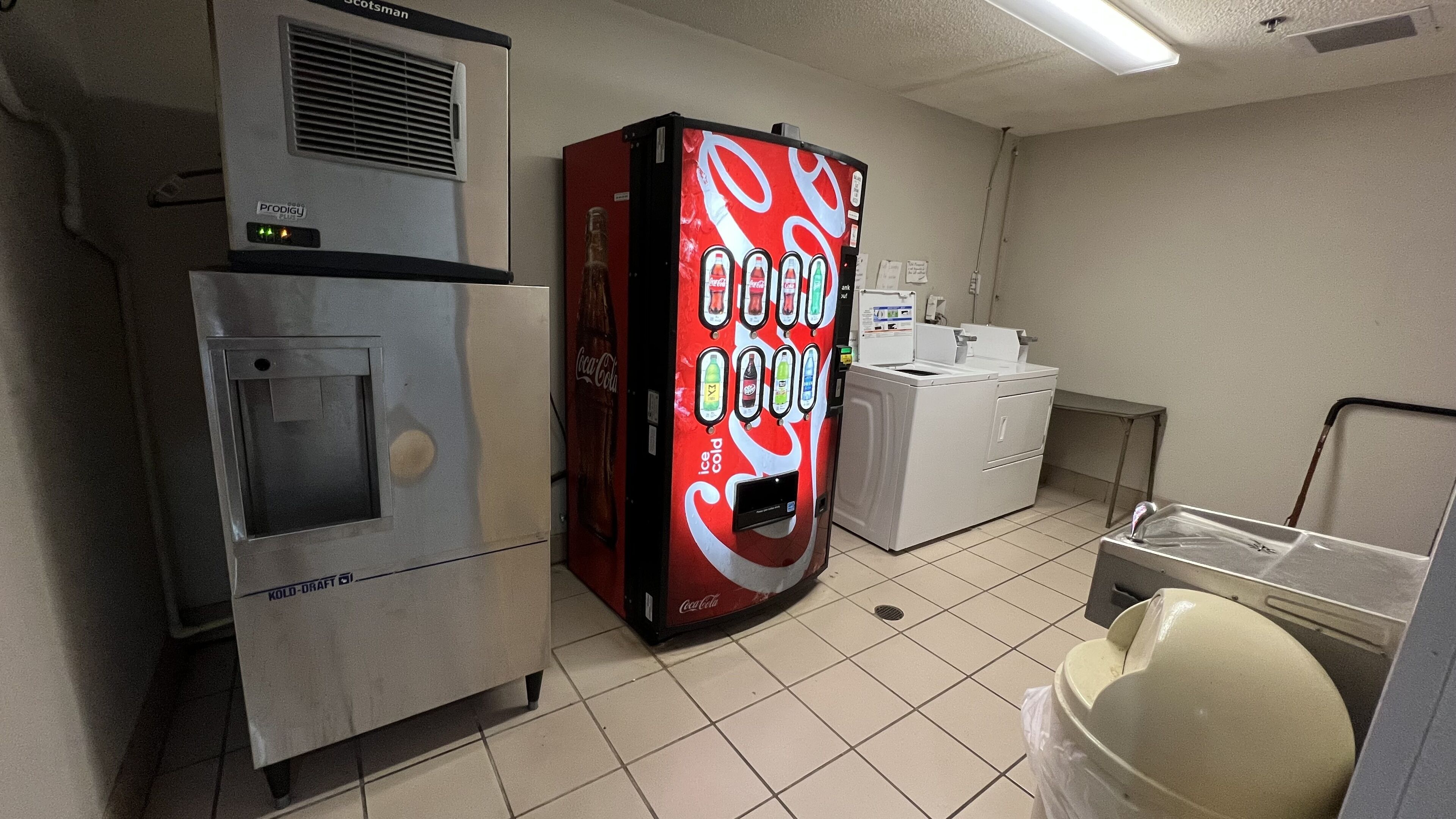 Een kitchenette met een koelkast, automaat en wasmachine.