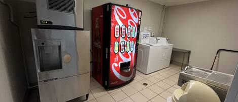 Een kitchenette met een koelkast, automaat en wasmachine.
