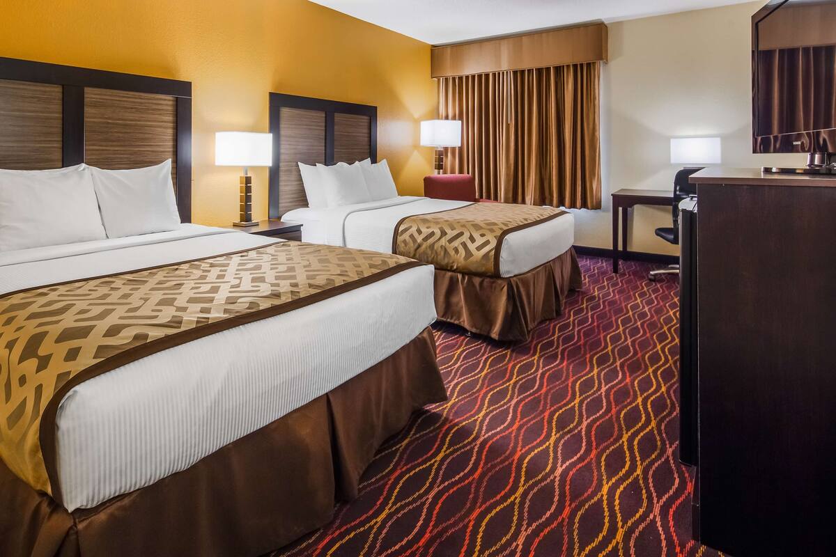 Une chambre d’hôtel avec deux lits, un bureau et une télévision.