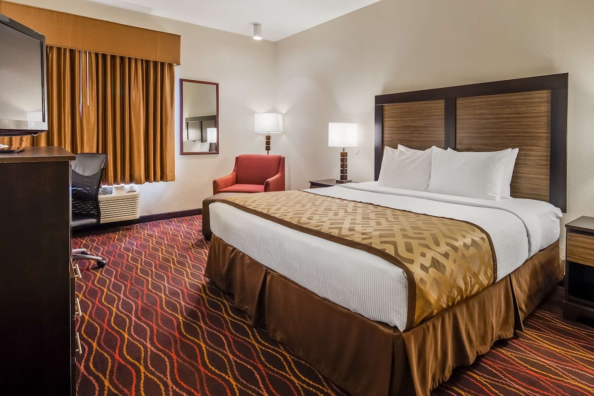 Une chambre d’hôtel avec un grand lit, un bureau avec une chaise, une télévision et deux lampes de chevet.