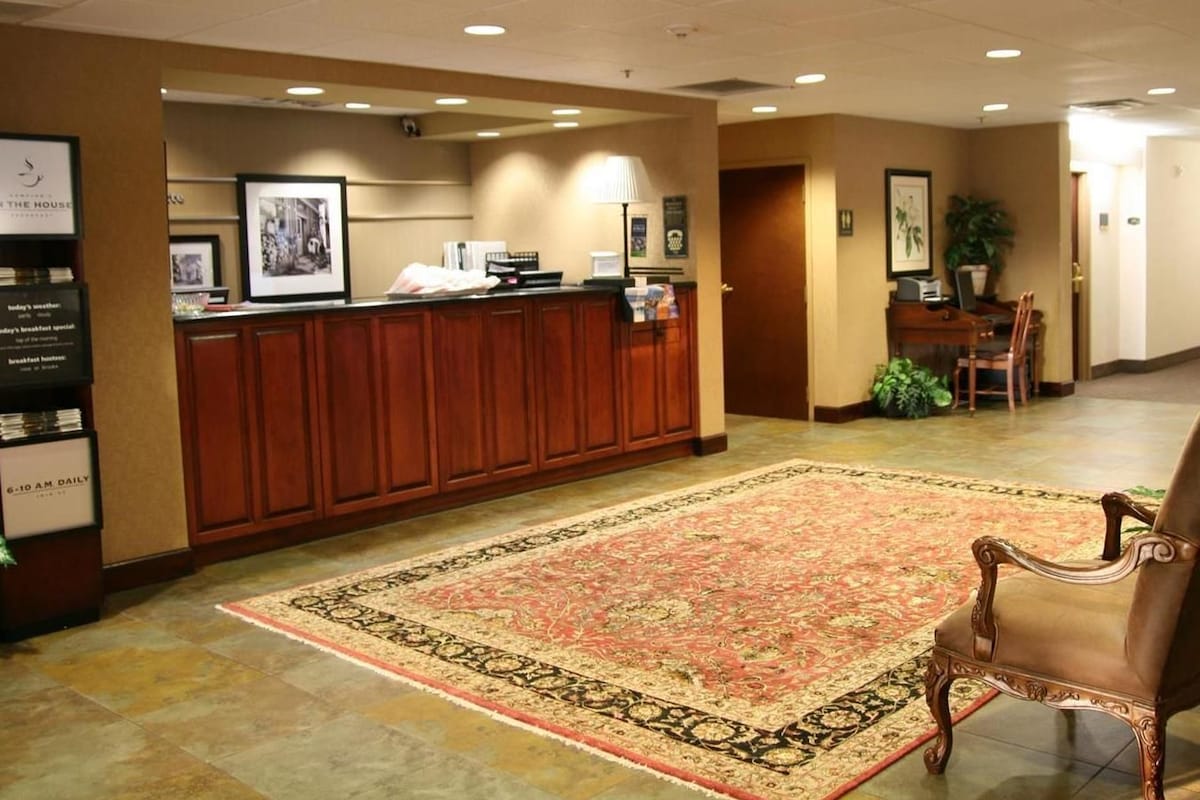 A reception area with a wooden counter, a patterned rug, and a classic chair.