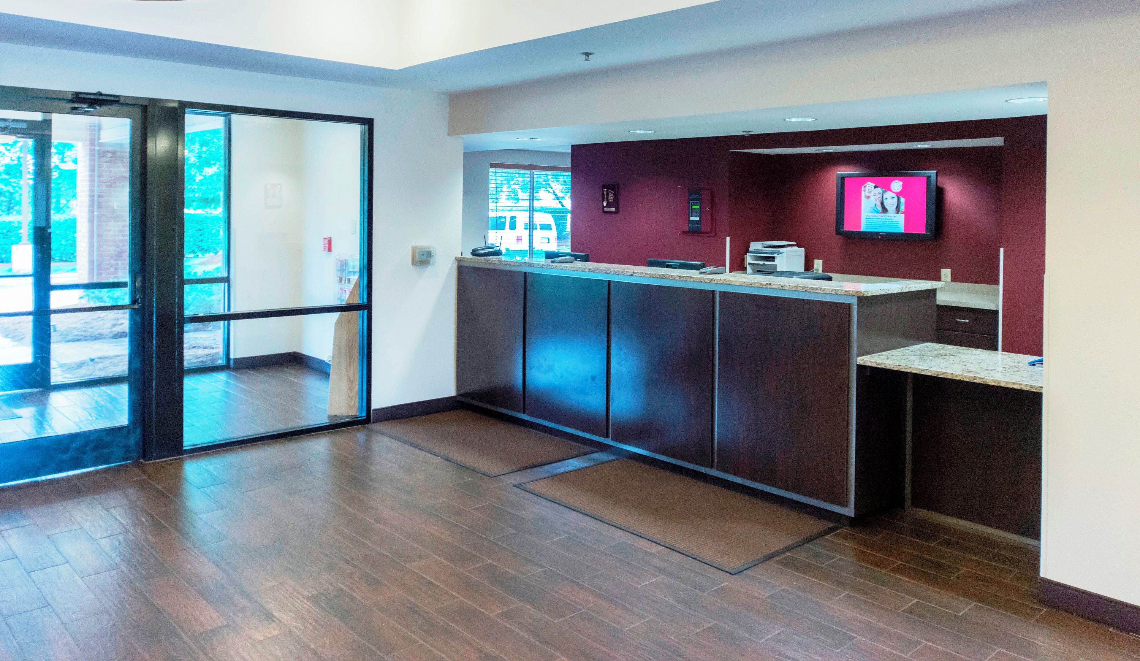 A reception area with a glass door entrance, a reception desk, and a wall-mounted television.