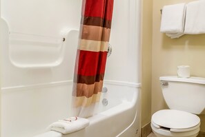 A bathroom with a bathtub, a toilet, and a shower curtain. - Red Roof Inn PLUS+ Raleigh Downtown – NCSU/Conv Center (Raleigh)