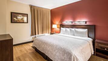A hotel room with a bed, a nightstand, a lamp, and a picture on the wall.
