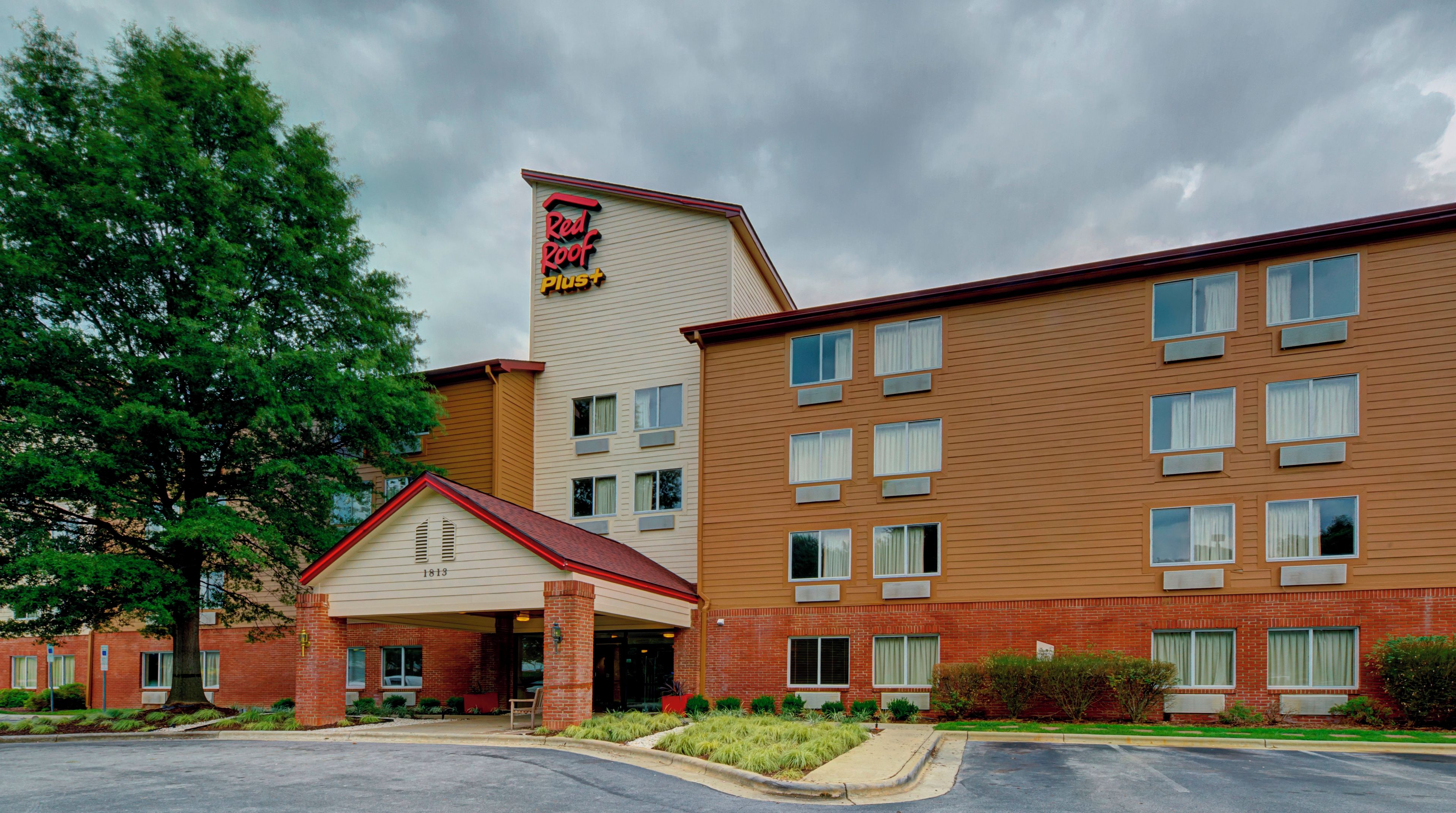 A Red Roof Plus hotel with a brick facade, a separate entrance building, and a parking lot.