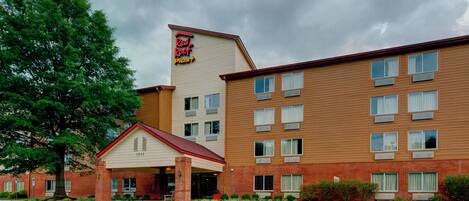 A Red Roof Plus hotel with a brick facade, a separate entrance building, and a parking lot.