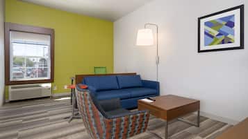 A room with a blue sofa, a patterned armchair, a wooden table, and a floor lamp.