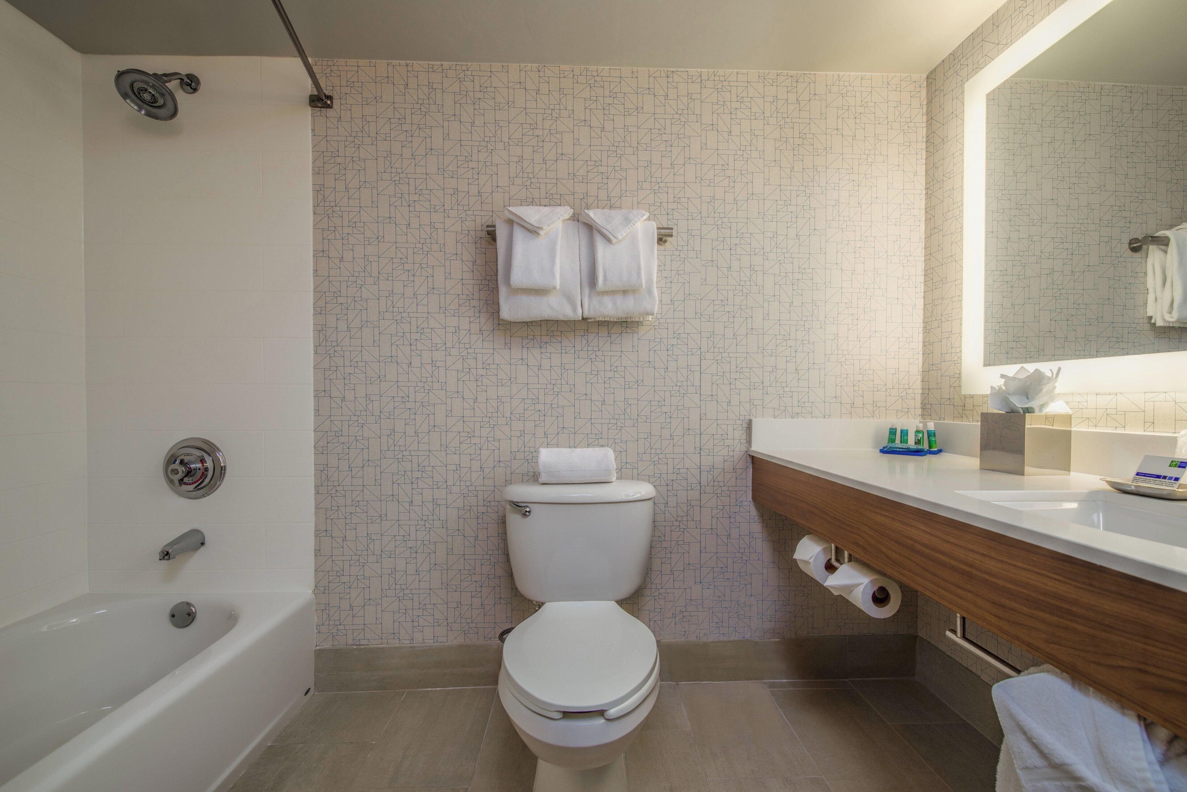 A bathroom with a bathtub, toilet, and vanity with a mirror.