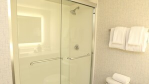 A modern bathroom with a glass shower enclosure, a white toilet, and a towel rack with towels. - Holiday Inn Express Hotel & Suites Phoenix-Airport by IHG (Phoenix)