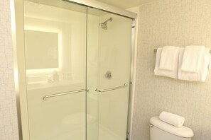 A modern bathroom with a glass shower enclosure, a white toilet, and a towel rack with towels. - Holiday Inn Express Hotel & Suites Phoenix-Airport by IHG (Phoenix)