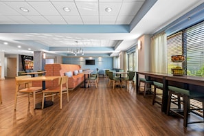 A spacious indoor area with wooden flooring, seating arrangements, and a bar counter. - Hampton Inn Birmingham/Trussville (Birmingham)