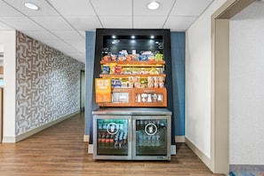A vending machine with snacks and drinks, a sign with a message, and a Coca-Cola refrigerator. - Hampton Inn Birmingham/Trussville (Birmingham)