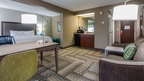 A hotel room with a bed, desk, chair, kitchenette, and a sofa. - Hampton Inn Dickson (Dickson)