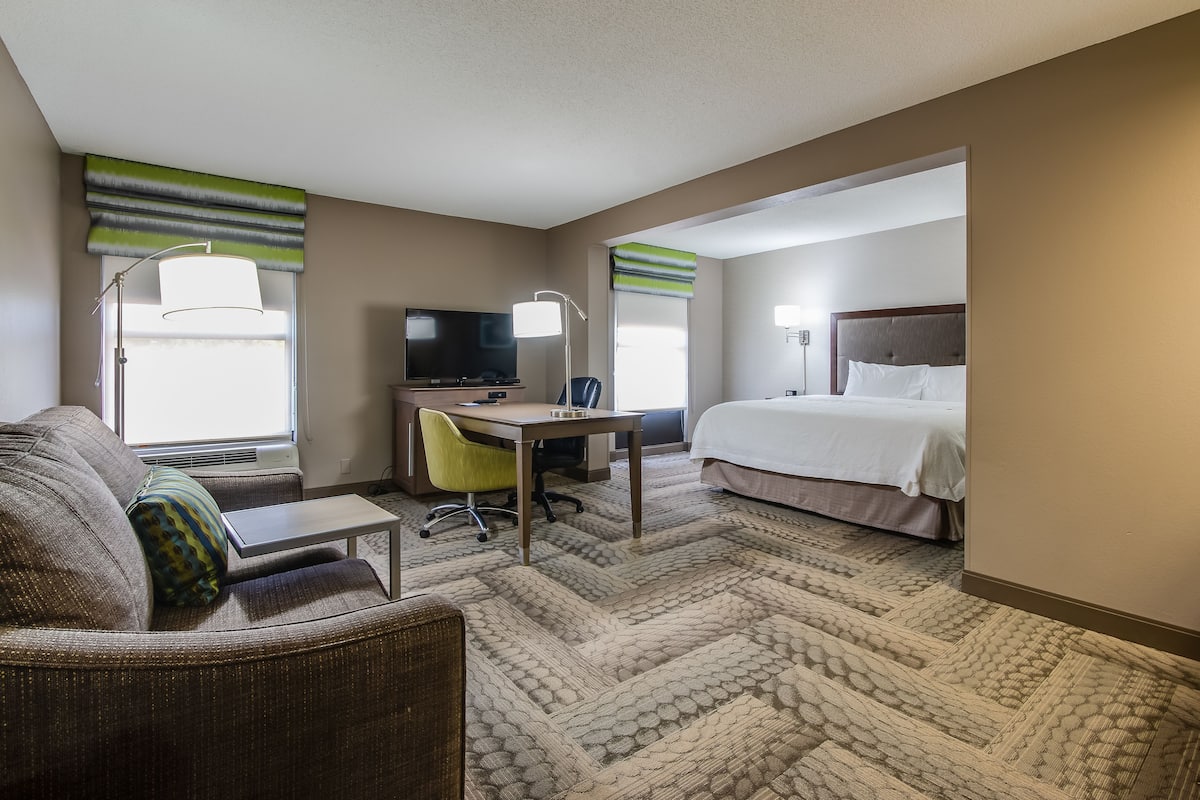 A hotel room with a bed, a desk, a chair, a television, and a window with curtains.