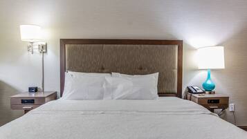 Una cama bien hecha con sábanas blancas, dos mesitas de noche con lámparas y un cabecero de madera.