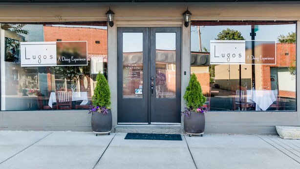 A storefront with a sign reading "Lugos A Dining Experience" and a contact number. - Hampton Inn Dickson (Dickson)