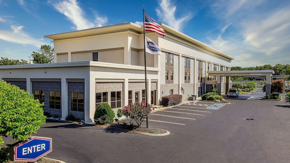 A modern building with a welcoming entrance, an American flag, and a 'Welcome' sign.