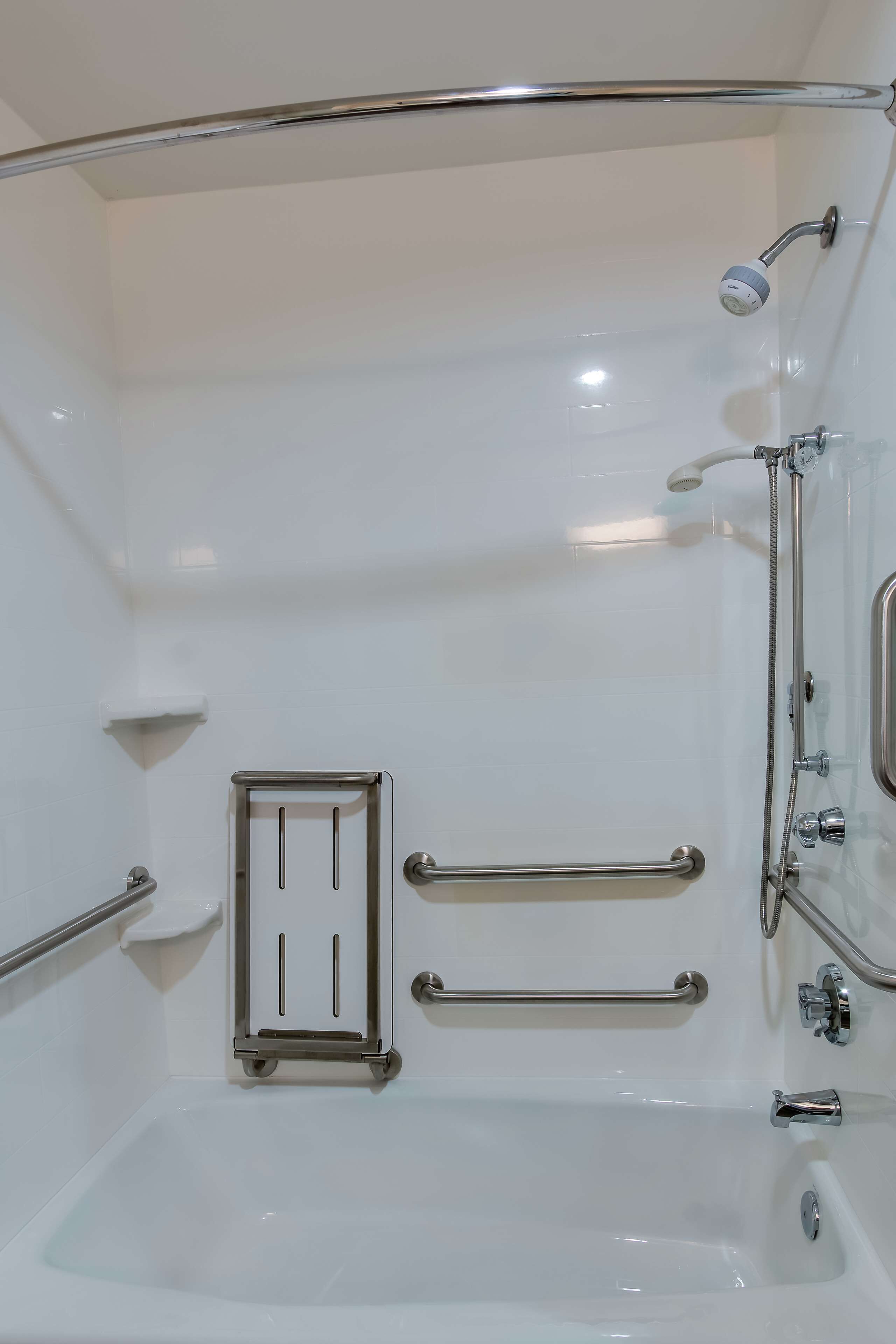Un baño moderno con bañera, barras de apoyo, ducha y retrete.