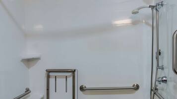 Un baño moderno con bañera, barras de apoyo, ducha y retrete.