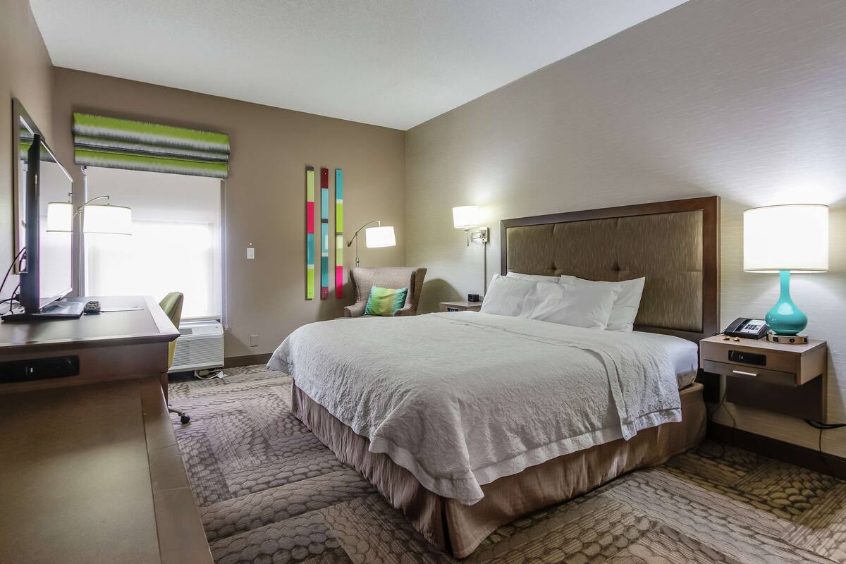 A hotel room with a large bed, bedside tables, a desk, and a chair.