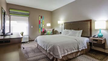 Una habitación de hotel con una cama grande, mesitas de noche, un escritorio y una silla.
