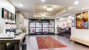 A modern lobby with a reception desk, a coffee station, a large red and yellow patterned rug, and a painting on the wall. - Hampton Inn Dickson (Dickson)