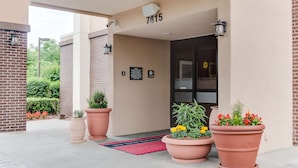 A hotel entrance with a number 7815 sign, large potted plants, and a red doormat. - Hampton Inn Bellevue / Nashville-I-40 West (Nashville)