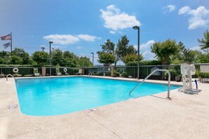 Relax by the clear pool surrounded by lounge chairs and a flagpole.