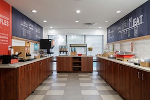 Una cocina moderna con armarios de madera, una isla central y una pared de pizarra con dibujos de comida.