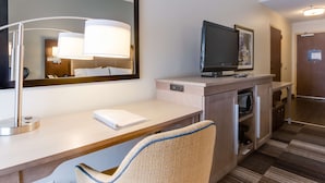 A hotel room with a desk, a chair, a television, a mirror, and a door. - Hampton Inn Bellevue / Nashville-I-40 West (Nashville)