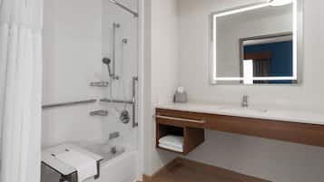 Un baño moderno con cabina de ducha, tocador con espejo y toallero.
